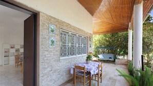 An outdoor patio with a table and chairs, a wooden ceiling, and a brick wall with decorative panels. - Villa Sole e Mare by BarbarHouse (Polignano a Mare)