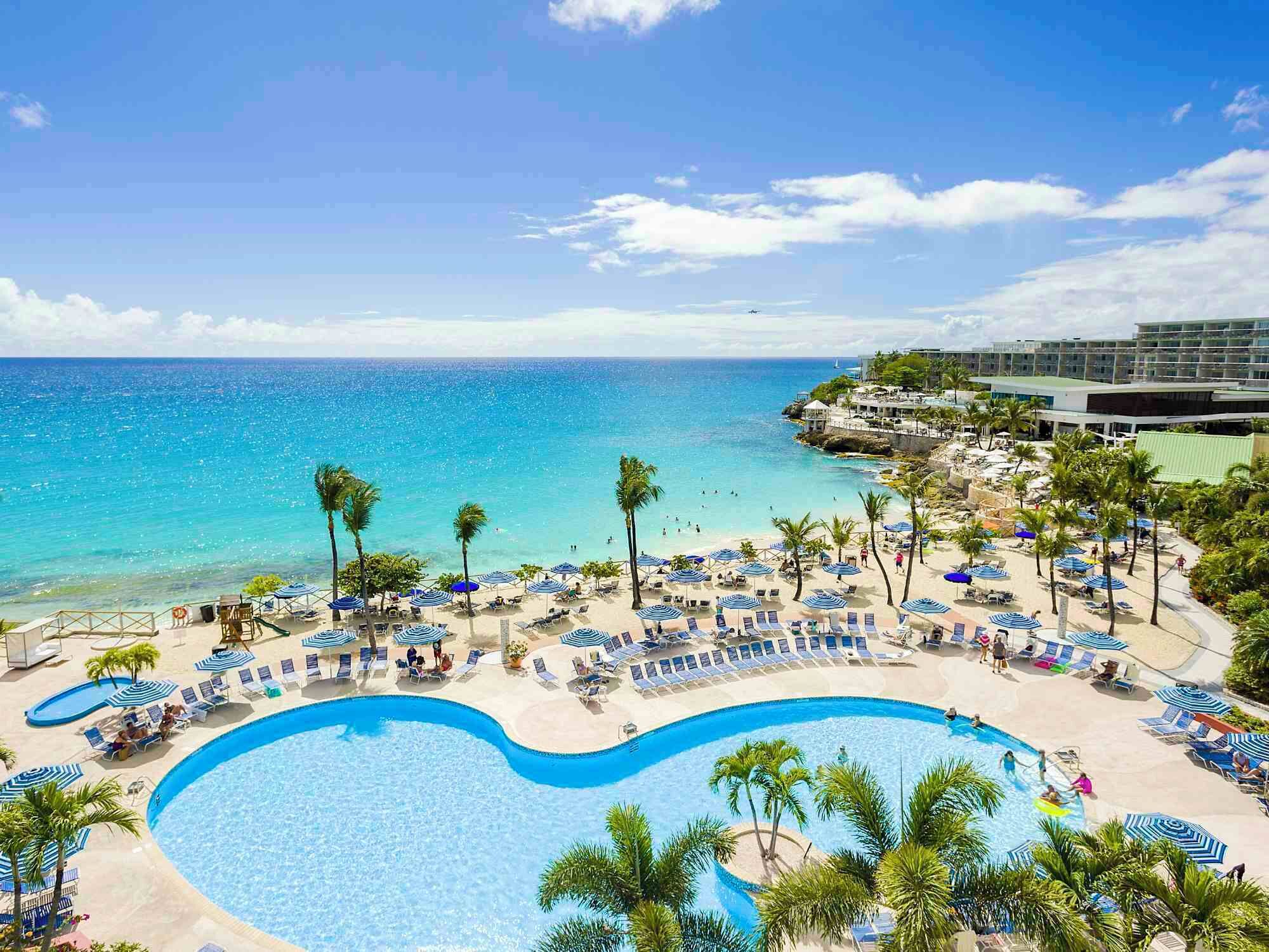A resort with a large pool, beach area, and ocean view.