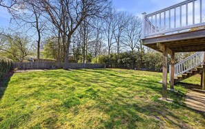 Ein Garten mit Holzterrasse, Steinmauer und Bäumen.
