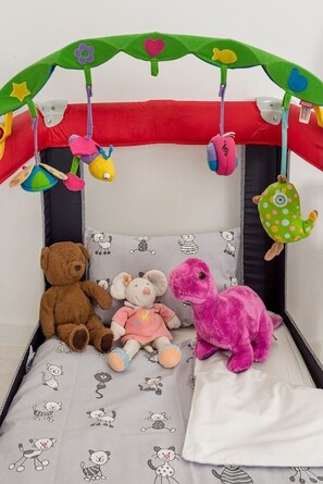 Ein Spielpen mit einem Teddybären, einem rosa Dinosaurier und einem rosa Hasen.