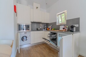 Eine kompakte Küche mit Waschmaschine, Geschirrspüler und einem Fenster über der Spüle.