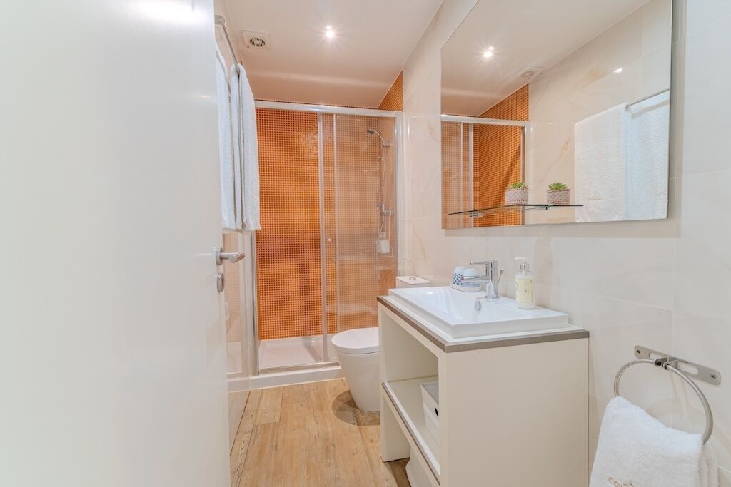 Une salle de bain moderne avec une douche à parois de verre, un lavabo blanc et un miroir au-dessus du meuble-lavabo.