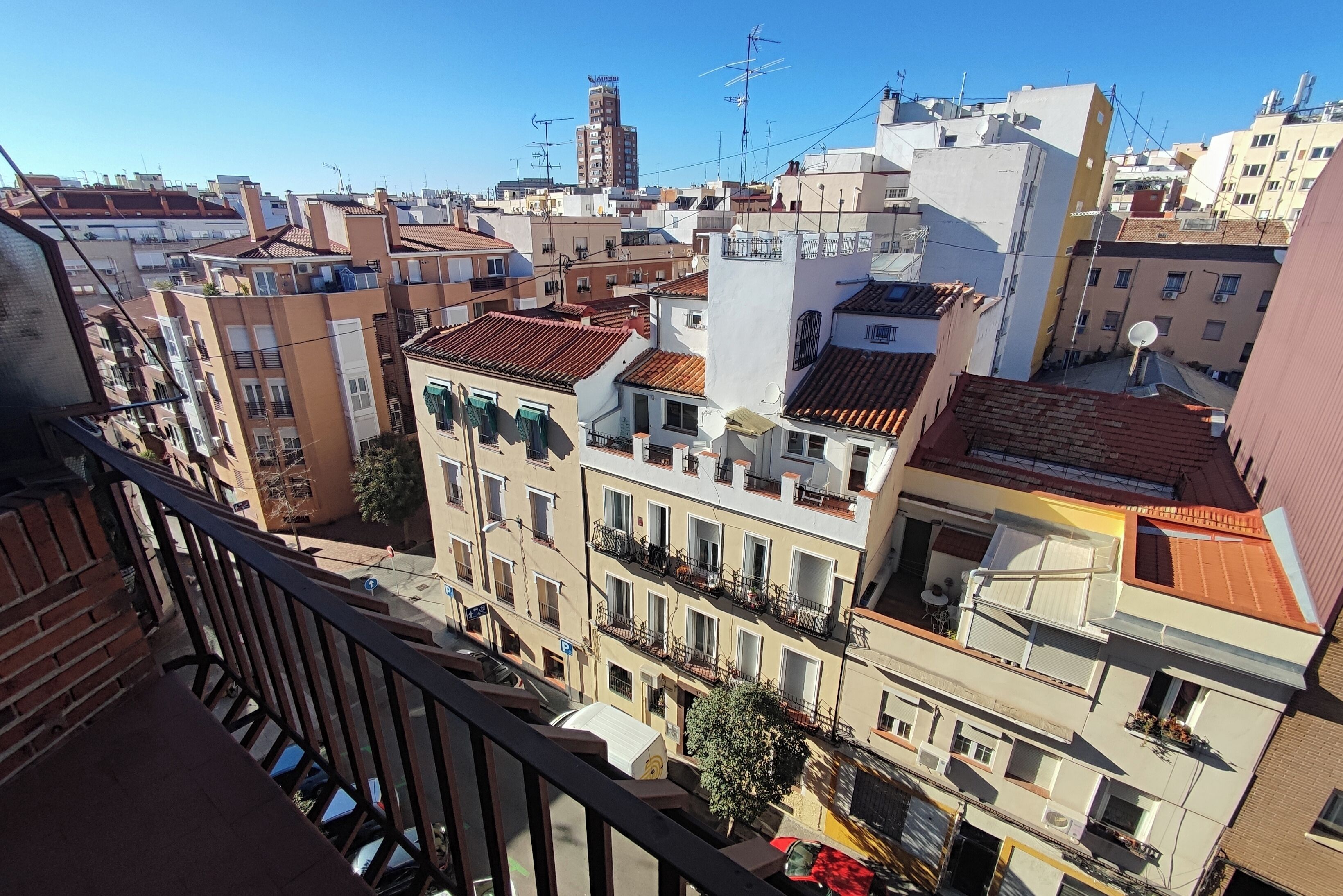 A residential area with multi-story buildings, balconies, and a clear blue sky.
