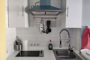 A kitchen with white cabinets, a stainless steel sink, a range hood, and various utensils hanging on the wall. - Madrid Salamanca • Bright apartment with a terrace (Madrid)
