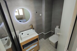 A bathroom with a round mirror, a sink, a toilet, and a shower area. - Madrid Salamanca • Bright apartment with a terrace (Madrid)