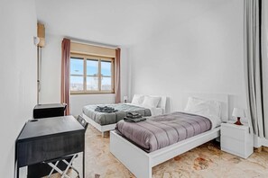 Ein modernes Schlafzimmer mit einem Bett, Nachttischen, einem Schreibtisch und einem Fenster mit Blick auf die Stadt.