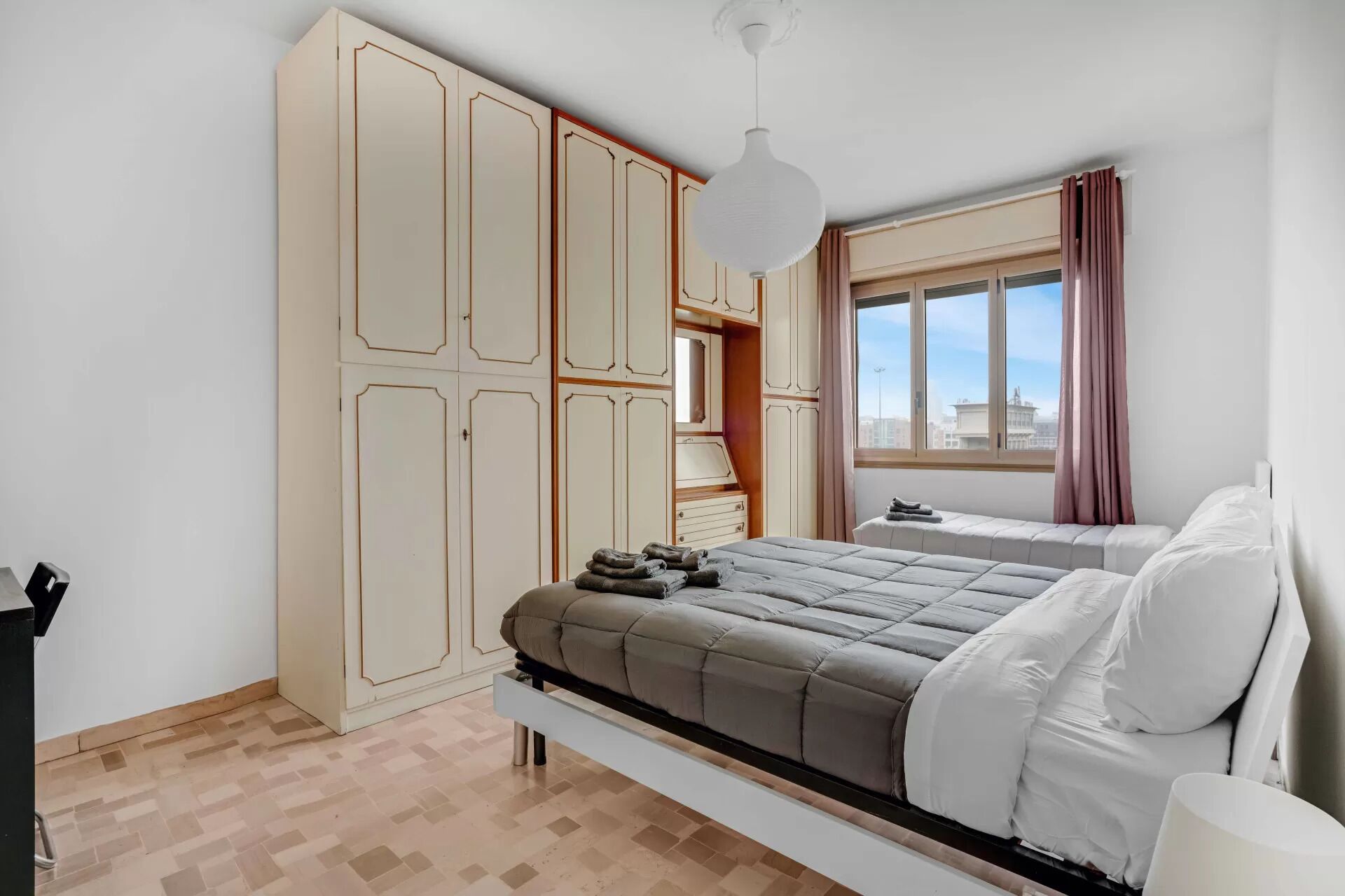 Une chambre à coucher comprenant un lit, une armoire, une fenêtre avec vue et un luminaire suspendu.