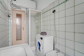 Ein Badezimmer mit Waschmaschine, Dusche und Toilette.
