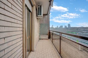 Ein Balkon mit Blick auf die Stadt, ein Fenster und eine Tür.