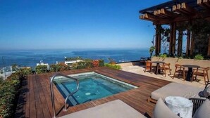 Ein Pool auf dem Dach mit Blick auf den Ozean, eine Holzterrasse und eine Sitzgelegenheit im Freien.