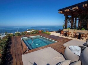 A rooftop pool with a view of the ocean, wooden deck, and outdoor seating area. - Sunset Lovers Paradise w/ rooftop shared pool & jacuzzi w/ perfect location (Puerto Vallarta)