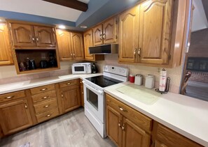 A kitchen with wooden cabinets, a microwave, an oven, and a sink. - Living on a budget? Look here! (Hays)