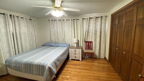 A bedroom with a bed, a nightstand, a chair, a wardrobe, and a ceiling fan. - Living on a budget? Look here! (Hays)