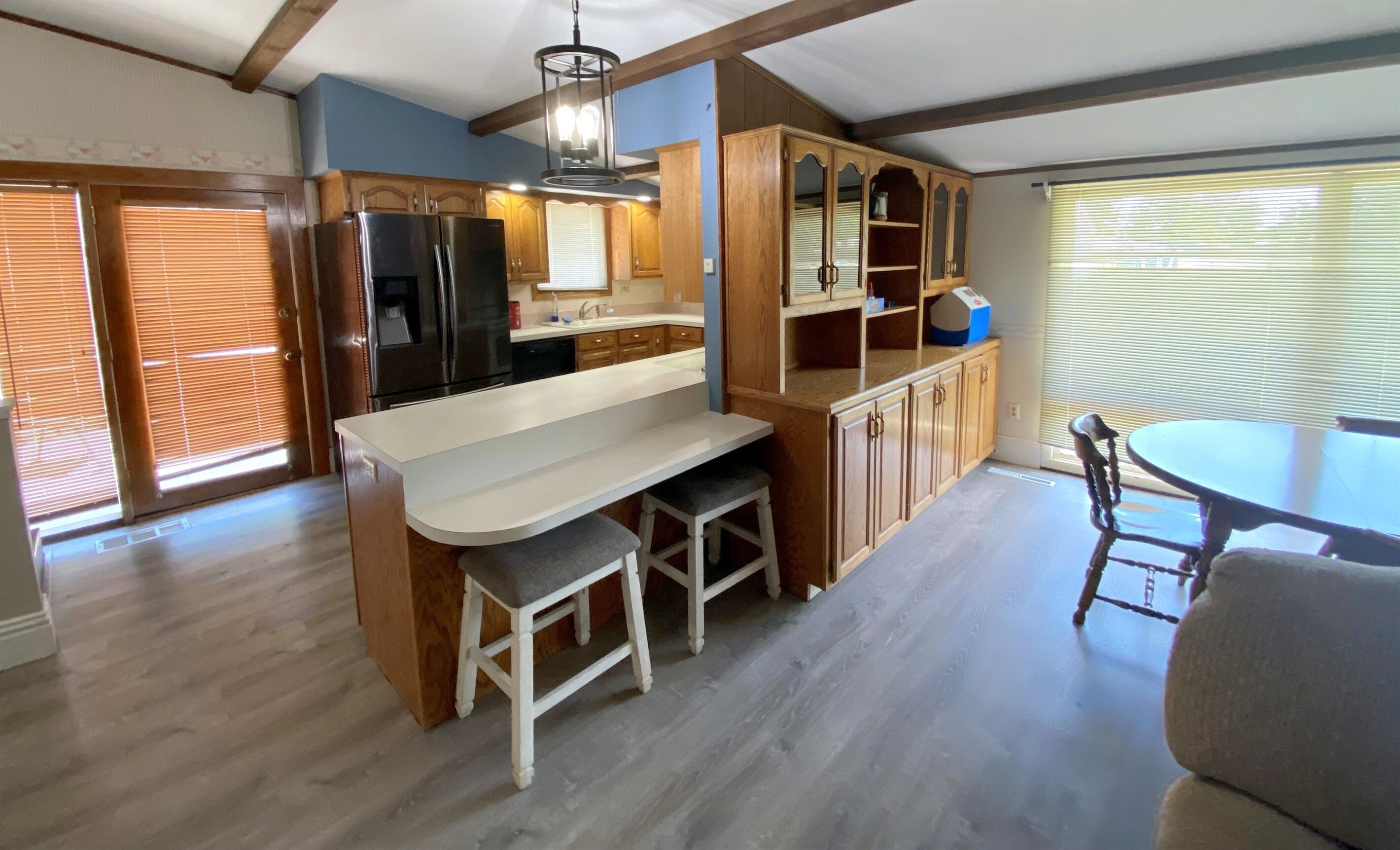 A kitchen with wooden cabinets, a white countertop, a built-in refrigerator, and a dining area with a table and chairs.