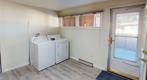 A laundry room with two white washing machines, a dryer, and a window above the machines. - Living on a budget? Look here! (Hays)