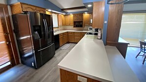 A kitchen with wooden cabinets, a black refrigerator, and a white countertop. - Living on a budget? Look here! (Hays)