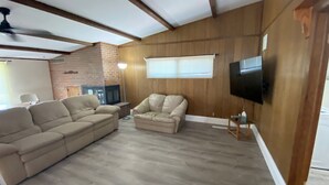 A living room with a sectional sofa, an ottoman, a TV mounted on the wall, and a fireplace. - Living on a budget? Look here! (Hays)