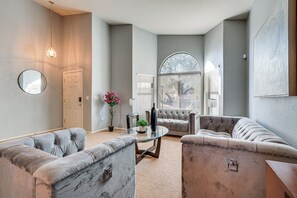 Ein Wohnzimmer mit einer Couch, einem Couchtisch, einer Topfpflanze und einem großen Fenster.