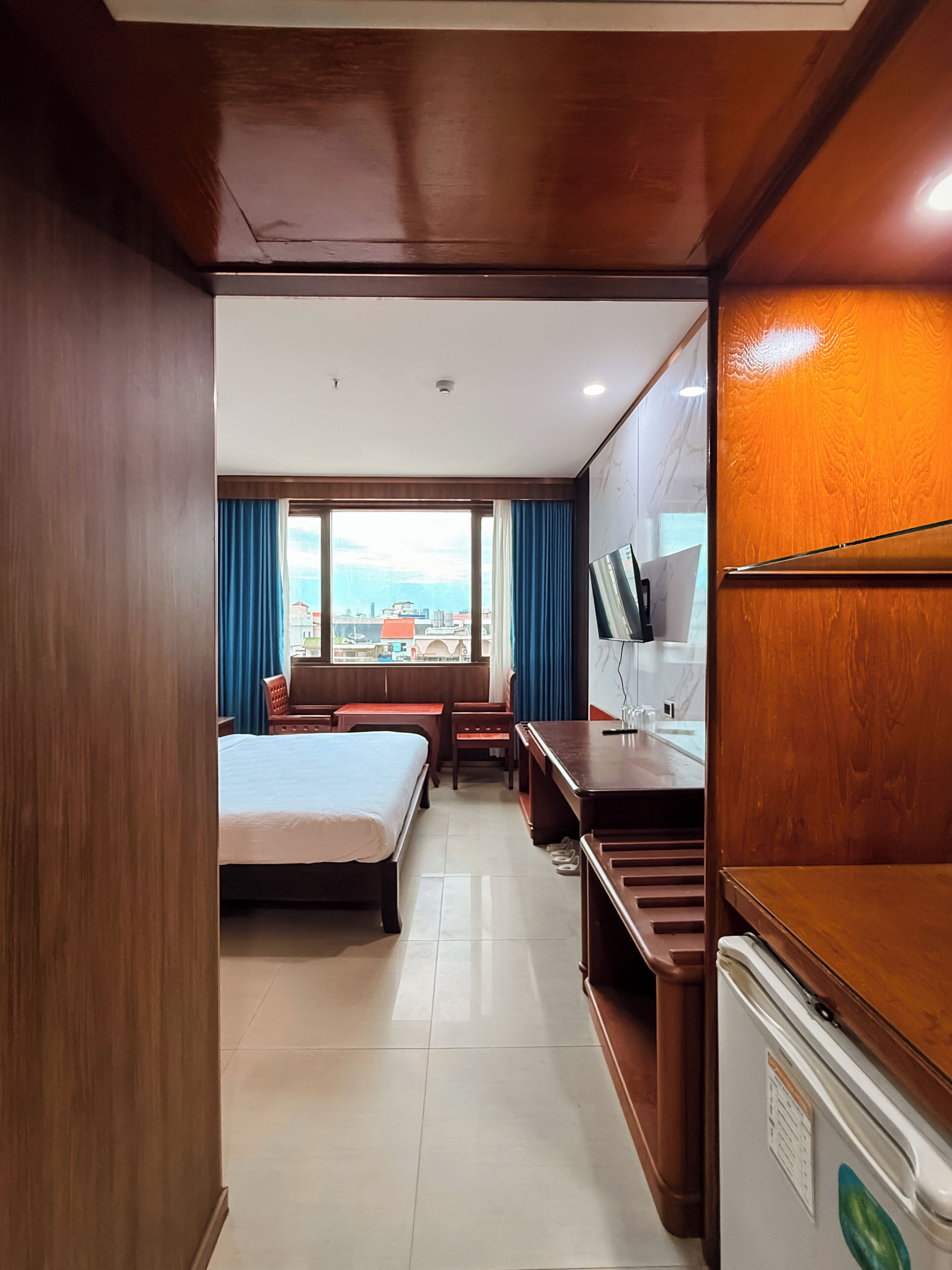 A hotel room with a bed, desk, chair, and a television.