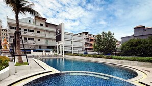 Una piscina con borde de azulejos, rodeada de un muro bajo y una palmera.