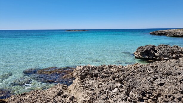 A coastal landscape with clear turquoise waters, rocky formations, and a distant island. - Two-Room Apartment in Salento Historic Center (Galatina)