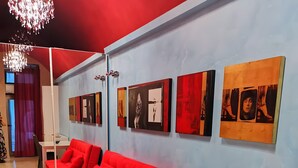 A modern room with a red sofa, white dining table, black chairs, and artwork on the walls. - Two-Room Apartment in Salento Historic Center (Galatina)
