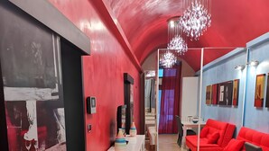 A modern interior with a red and white color scheme, a chandelier, and a red sofa. - Two-Room Apartment in Salento Historic Center (Galatina)