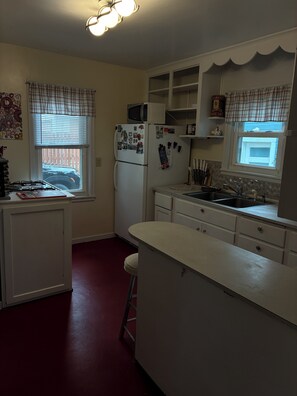 A compact kitchen with a refrigerator, microwave, and sink.