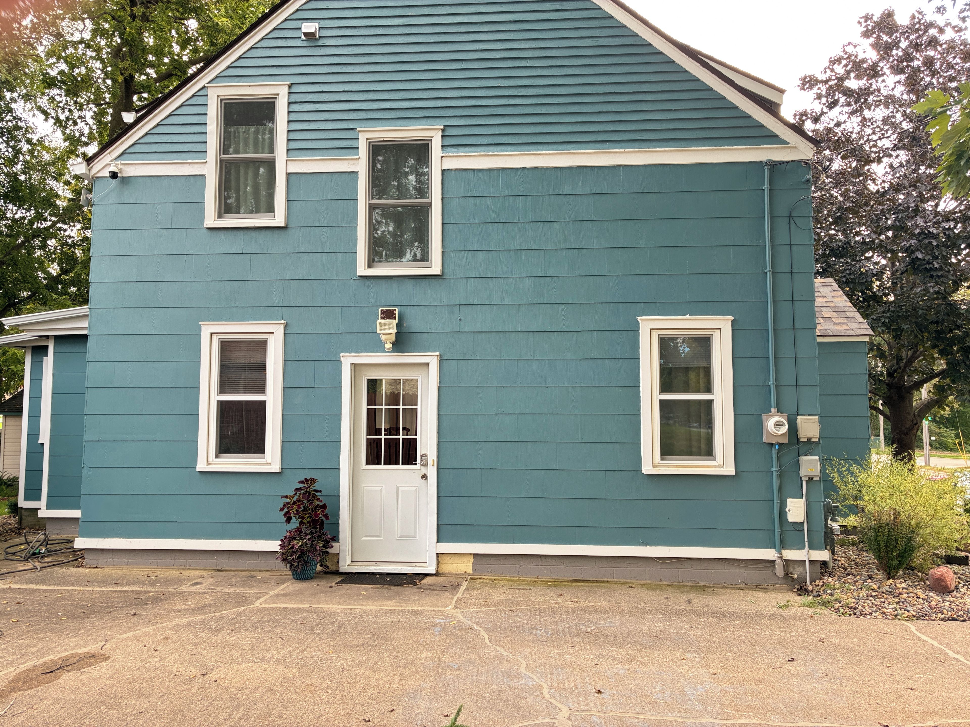 A two-story house with a front door, two windows on the ground floor, and a small porch area.