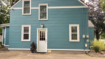 A two-story house with a front door, two windows on the ground floor, and a small porch area.