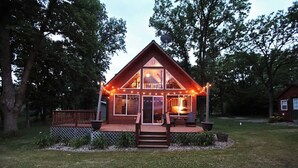 A two-story wooden cabin with a deck, large windows, and a satellite dish. - Leaf Lake Cabin, Henning MN (Henning)