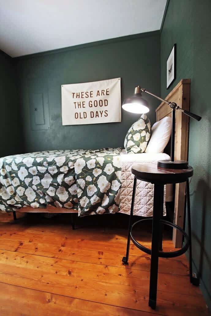 Um quarto com uma cama, uma mesa redonda, um abajur e uma placa na parede.