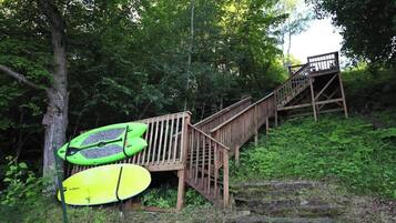 Una escalera de madera que sube una colina con dos kayaks apoyados al lado.