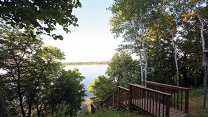 A wooden staircase leading to a deck overlooking a lake, surrounded by trees. - Leaf Lake Cabin, Henning MN (Henning)