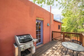 Ein Grill, ein Tisch und eine Terrasse mit Holzgeländer.