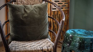A wicker chair with a green cushion and a small stool with a blue top. - Charming Railyard Adobe, Pet Friendly (Santa Fe)