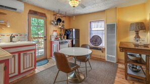 A compact kitchen with a dining area, a ceiling fan, and a window with a view. - Charming Railyard Adobe, Pet Friendly (Santa Fe)