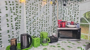 A tent interior with a table, a microwave, and various kitchen items.