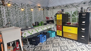 A tented kitchen area with a sink, microwave, and storage cabinets.