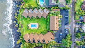Una vista aerea di un resort con piscina, diverse sistemazioni in stile bungalow e un'area parcheggio.