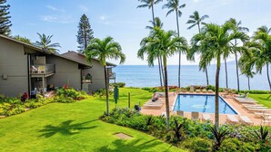 Una casa de dues plantes amb piscina, envoltada de palmeres i vista a l'oceà.