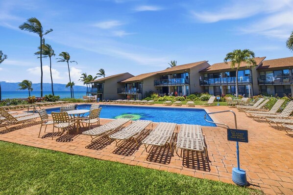 Un resort con piscina, lettini e vista sull'oceano.