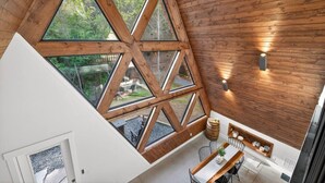Un intérieur moderne avec un plafond en bois, de grandes fenêtres et un coin repas comprenant une table et des chaises.