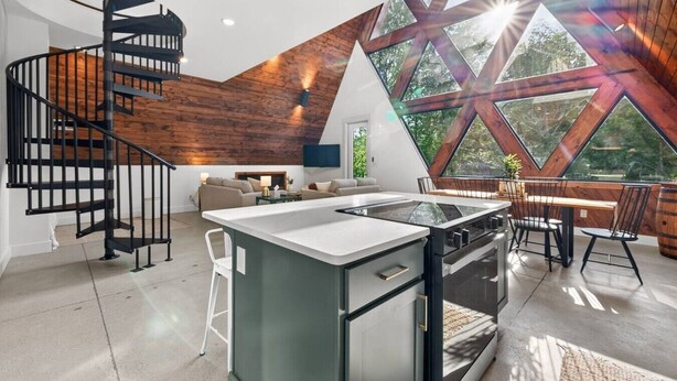 Une cuisine moderne dotée d’un îlot central, d’un escalier en colimaçon et de grandes fenêtres.