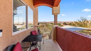 Un balcone con tavolo e sedie, vista sul paesaggio desertico e cielo sereno.