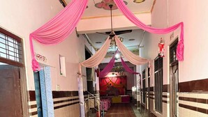 Un pasillo con cortinas rosadas, alfombra estampada y un candelabro.