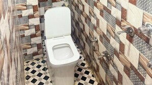 Un baño con inodoro, ducha y calentador de pared.