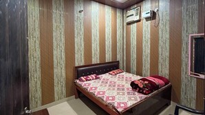 Un dormitorio con una cama, una silla, un ventilador de techo y un equipo de aire acondicionado.