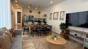 Een moderne woonkamer met een bank, salontafel en eethoek.