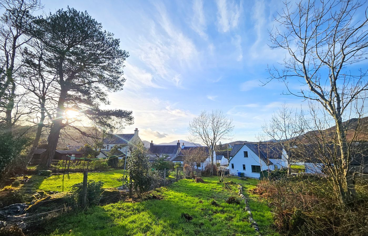Un paysage rural avec des maisons, un champ verdoyant et un ciel dégagé.